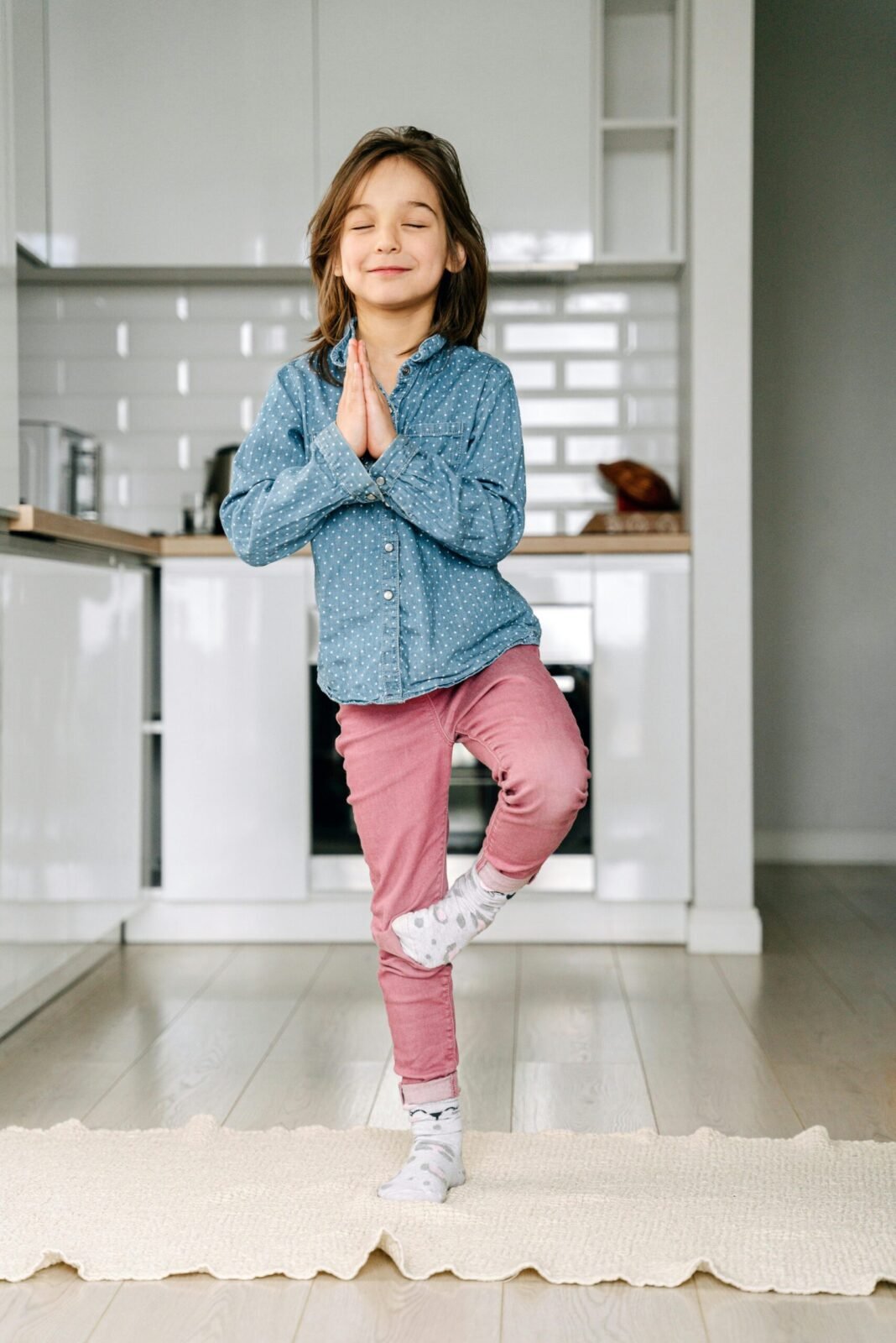 Little Girl Standing on One Leg on Yoga Mat in Kitchen